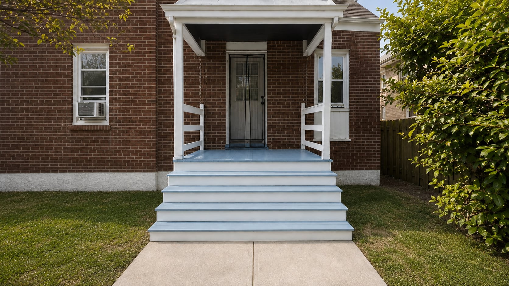 Finished blue front porch and wide exterior stairs at a brick home